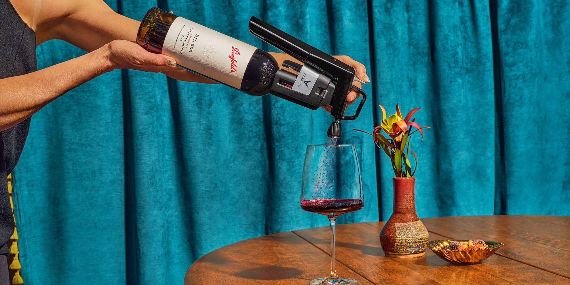 Un bras verse du vin dans un verre à travers un aérateur.
