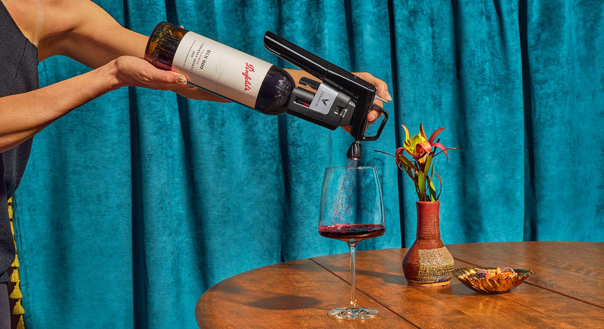Un bras verse du vin dans un verre à travers un aérateur.